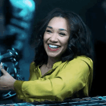 a woman in a yellow shirt is smiling in a dark room .