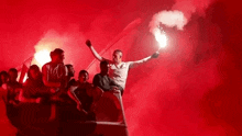 a man is holding a flare in front of a crowd of people in a boat .