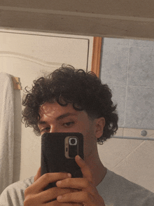 a man with curly hair is taking a picture of himself with his phone