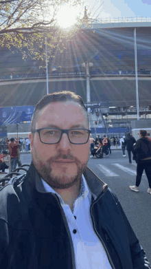 a man wearing glasses is standing in front of a stadium that says uefa