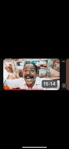 a phone screen shows a man with a mustache smiling at the camera with the time of 15:14