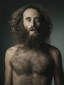 a shirtless man with a beard and curly hair makes a surprised face