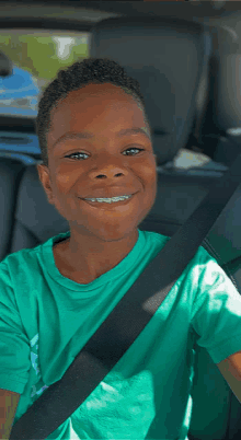 a young boy wearing braces and a green shirt is smiling in the back seat of a car