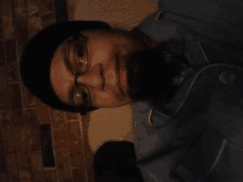 a man wearing glasses and a beanie looks down at something