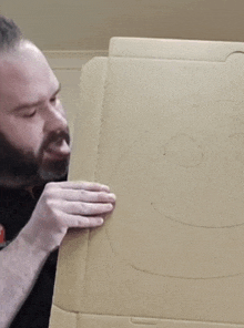 a man is holding a cardboard box with a drawing of a smiley face on it