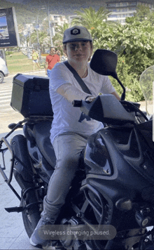 a man sitting on a motorcycle with the words wireless charging paused above him