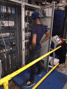 a man wearing a blue hat is standing in front of a large electrical box