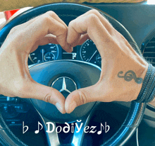 a person is making a heart shape with their hands in front of a mercedes steering wheel