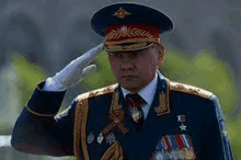 a man in a military uniform is saluting in front of a building .