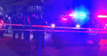 a group of police officers are standing in front of a police car in a crime scene .