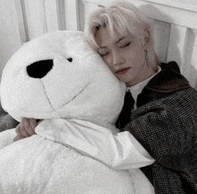 a man laying on a bed holding a large white teddy bear