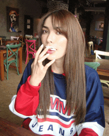 a woman wearing a tommy jeans shirt is sitting at a table