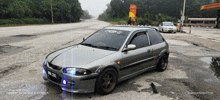 a silver car is parked in front of a gas station with a sign that says ' shell ' on it