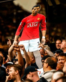 a fan holds up a cardboard cutout of ronaldo wearing a red aig shirt