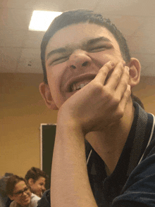 a young man laughs with his hand on his chin