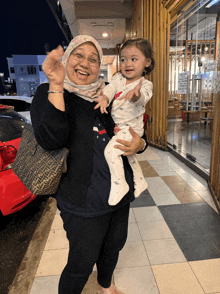 a woman holding a baby in front of a sign that says no smoking