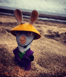 a stuffed animal wearing a yellow hat and a purple jacket