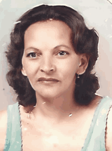 a woman in a blue tank top is looking at the camera with a serious look on her face