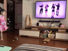 a little girl is dancing in front of a large flat screen television