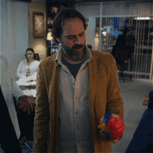 a man with a beard is holding a red and blue ball