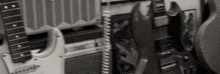 a black and white photo of a row of guitars hanging on a wall next to an amplifier .