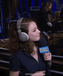 a woman wearing headphones is holding a microphone that says multi show on it