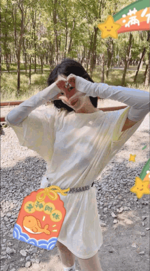 a woman in a white dress is making a heart shape with her hands while holding a purse with chinese writing on it