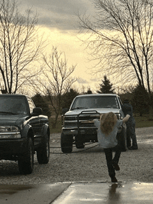 a little girl is standing in front of a truck that says ' chevrolet ' on the front