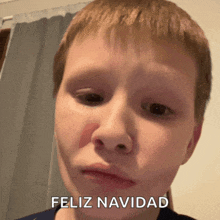 a young boy with a red spot on his face and the words feliz navidad on the bottom