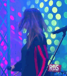 a woman is singing into a microphone with rds written on the bottom right