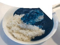 a bowl of rice and blue sauce with a spoon