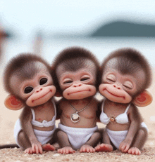three baby monkeys are sitting on a beach and smiling