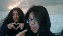 two girls making a heart shape with their fingers