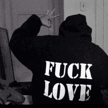 a person wearing a black hoodie with the words `` fuck love '' written on the back .