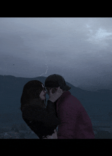 a man and woman kissing in front of a lightning strike