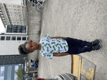 a young boy wearing sunglasses and a shirt with pickles on it is standing in a parking lot