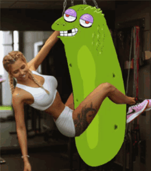 a woman is hanging upside down on a green pickle punching bag