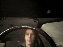 a man is driving a car in the rain and his face is reflected in the windshield