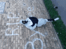 a person laying on a brick sidewalk with graffiti on it including one that says ' goodbye '