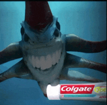 a tube of colgate toothpaste with a shark behind it