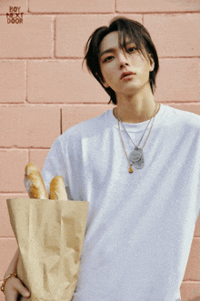 a young man in a white shirt is holding a bag of bread with boy next door written on the bottom