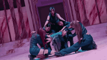 a group of women are kneeling in a circle around a man on a stage .