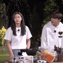 a man and a woman are standing in front of a table with a box of tissues that says ' vegetables '