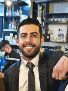 a man with a beard is wearing a suit and tie and smiling .