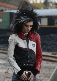 a man wearing a red and white leather jacket with a shield on the sleeve