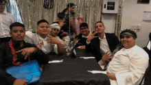 a group of young men are posing for a picture while sitting around a table