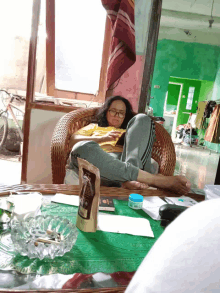 a woman sits in a chair reading a book with a bag of coffee on the table