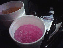 two cups of purple liquid next to a bottle of alcohol .