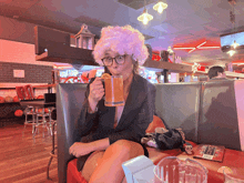 a woman wearing a wig and glasses is drinking from a mug