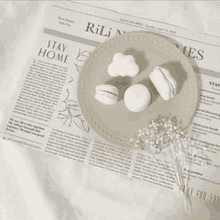 a plate of macarons sitting on top of a newspaper on a table .